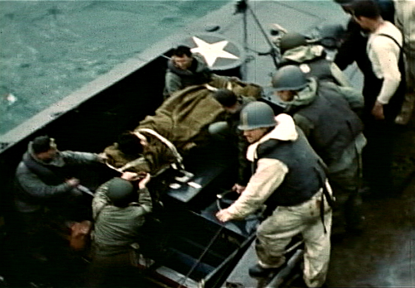 Fig. 14: Robert Capa, bottom left, aboard LCVP from USS Samuel Chase, assisting with transfer of casualty, D-Day, frame from film by David T. Ruley