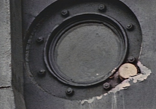 Figure 7. The intact base of a projectile (?) lodged into the porthole mounting ring on the forward face of LCI(L)-94’s pilot house. Still from David T. Ruley film clip.